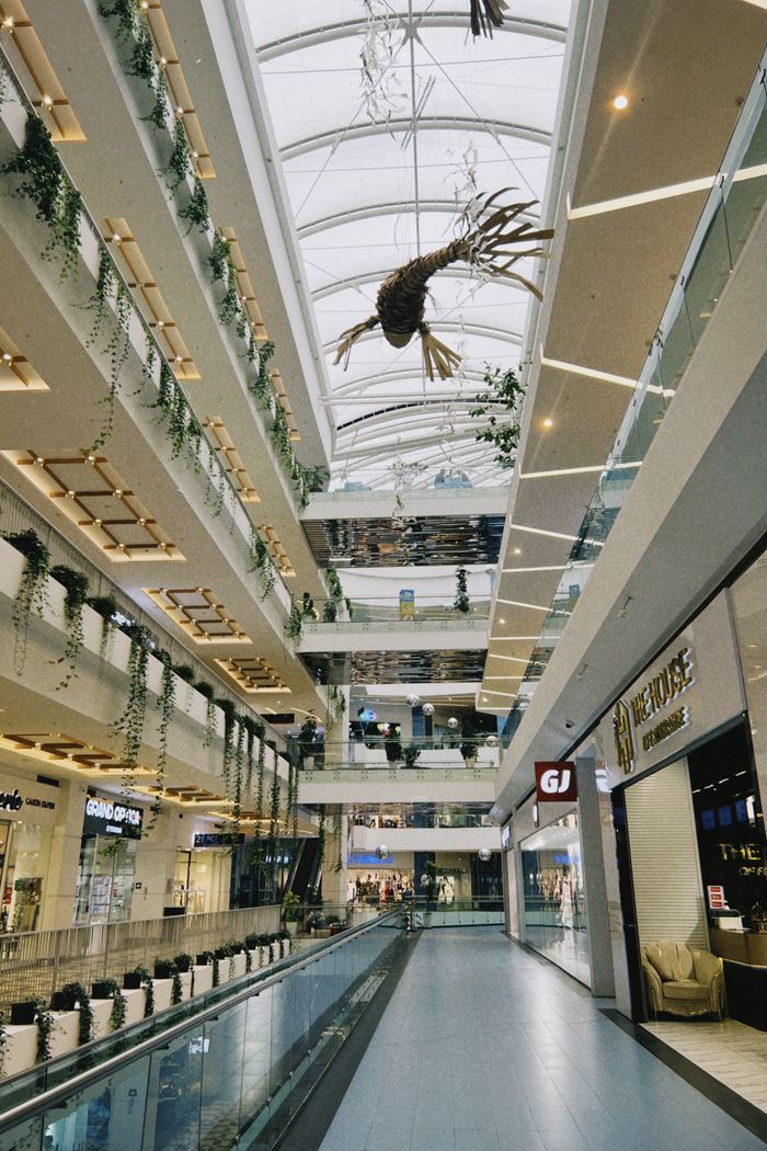 Spacious indoor shopping mall with plants and modern design in Almaty, Kazakhstan.