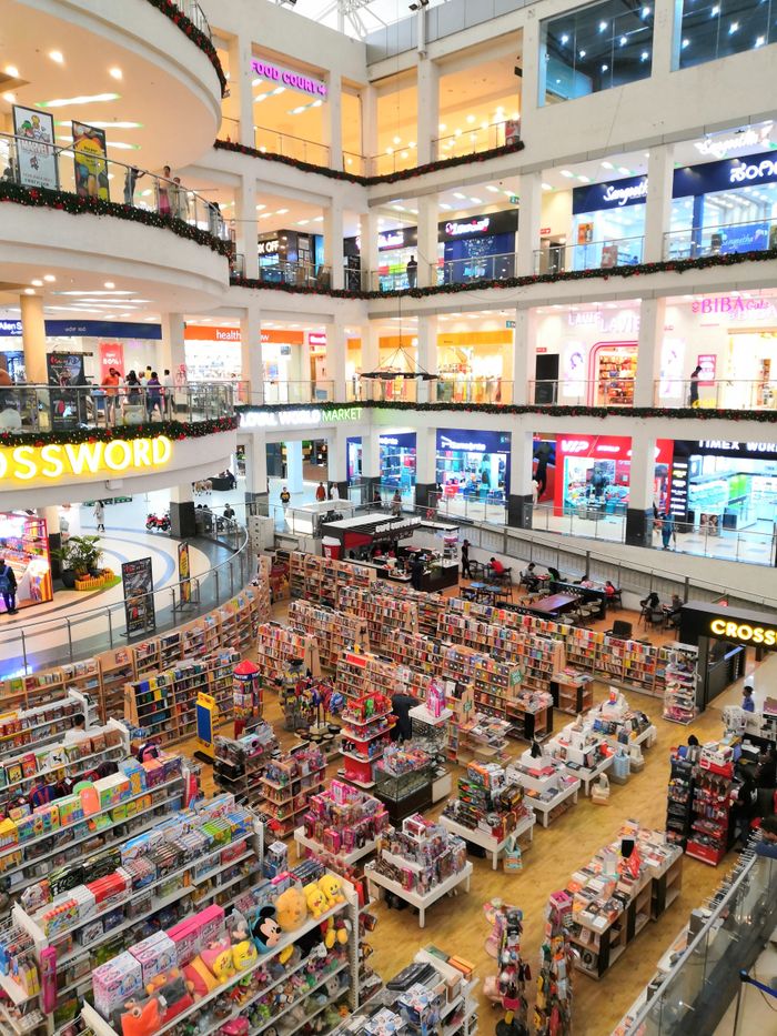 Bright daytime view of a bustling shopping mall with multiple stores and levels.